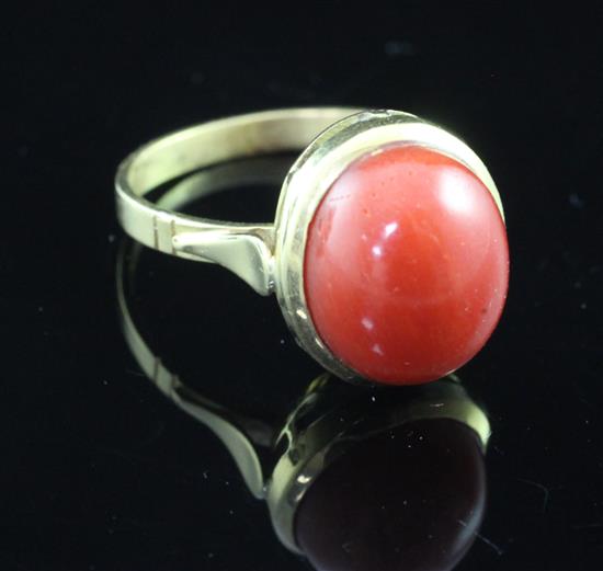 An 18ct gold and oval cabochon coral ring, size M.